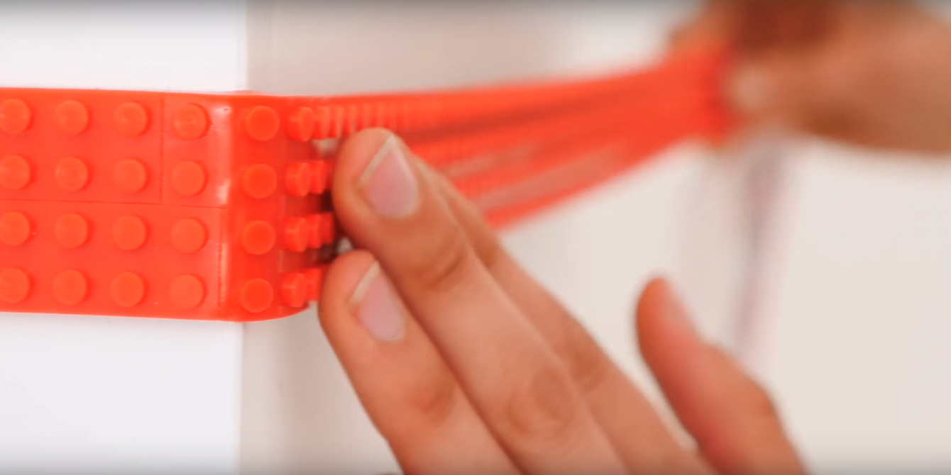 Hand sticking lego tape to wall