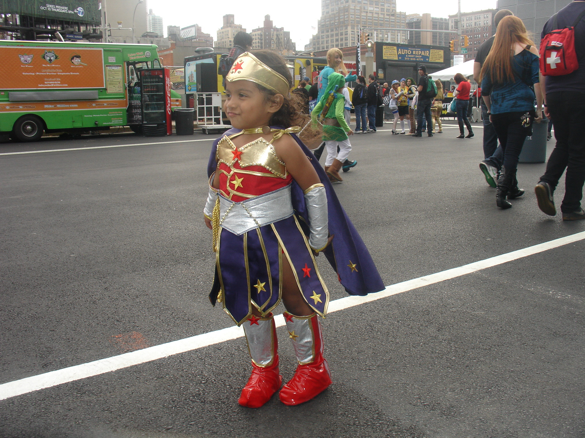 5 year old her standing in street wearing wonder woman costume